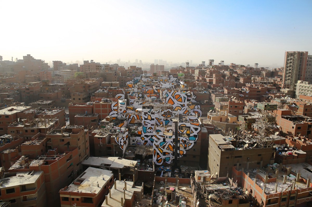 eL Seed’s Zaraeeb community mural in Cairo on 40-plus buildings that reads: ‘Anyone who wants to see the sunlight clearly needs to wipe his eye first.’ 