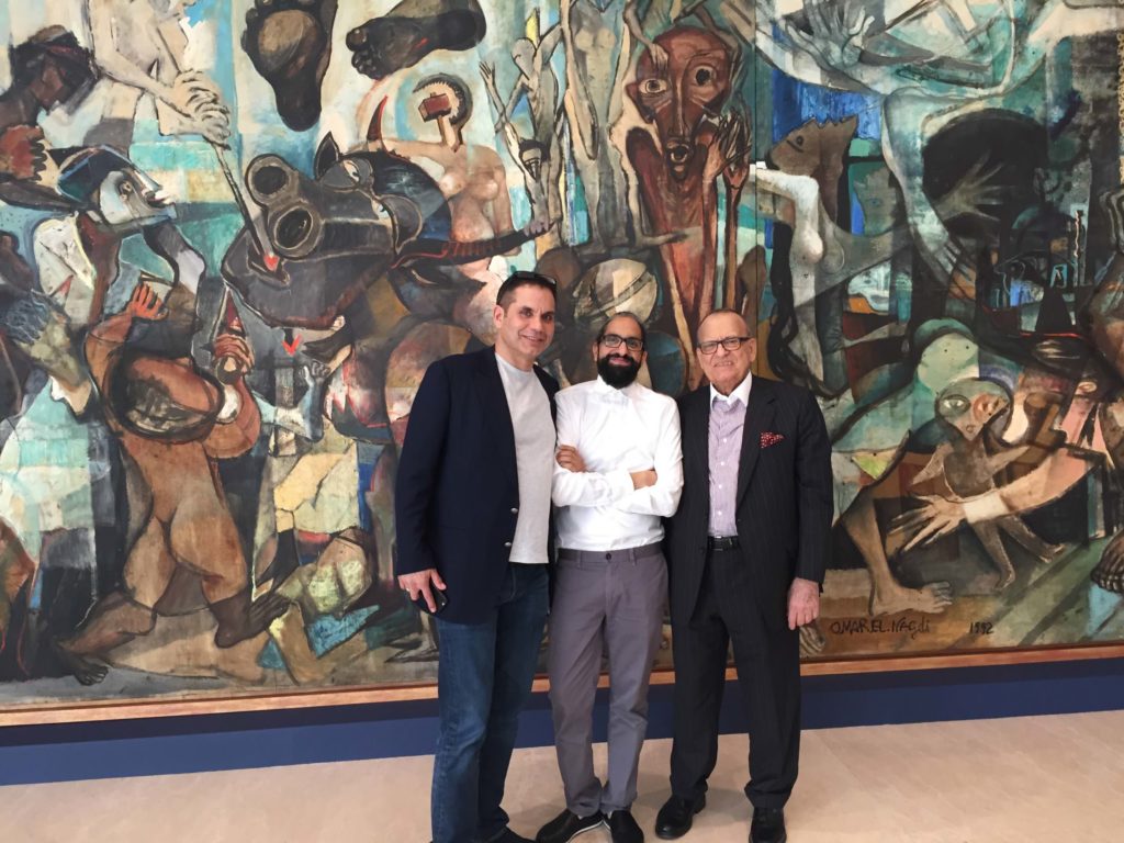 Dr Ramzi Dalloul and Dr Basel Dalloul with the author at a Christie’s auction in Dubai in March 2016. Artwork in the background: Omar El-Nagdi (1931-2019, Cairo, Egypt), Sarajevo, 1992.